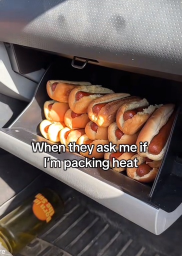 A photo of a glovebox filled with hotdogs with the caption “When they ask me if I'm packing heat”